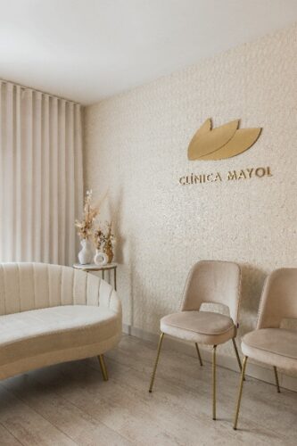 Sala de espera en color beige y dorados de la Clínica Mayol diseñada por el estudio de interiorismo Strada Interiors