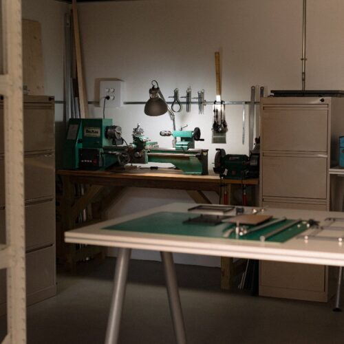 Taller con torno mecánico, herramientas y mesa de trabajo iluminada con luz puntual.