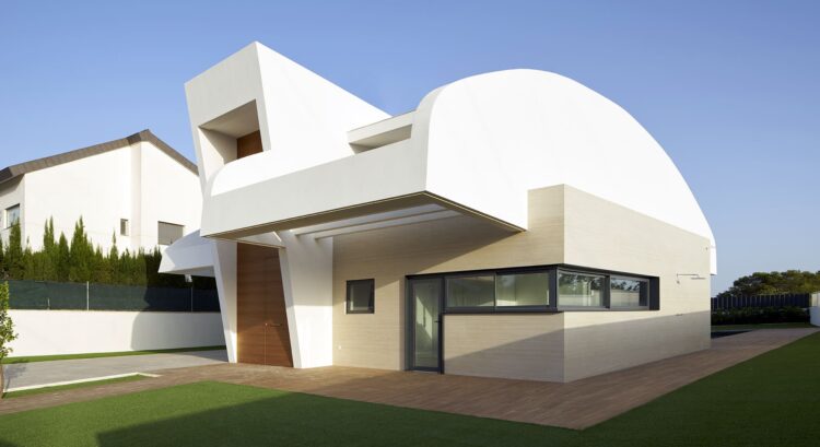 Fachada exterior con cubierta curva y contraste de materiales, porcelánico y mortero blanco.