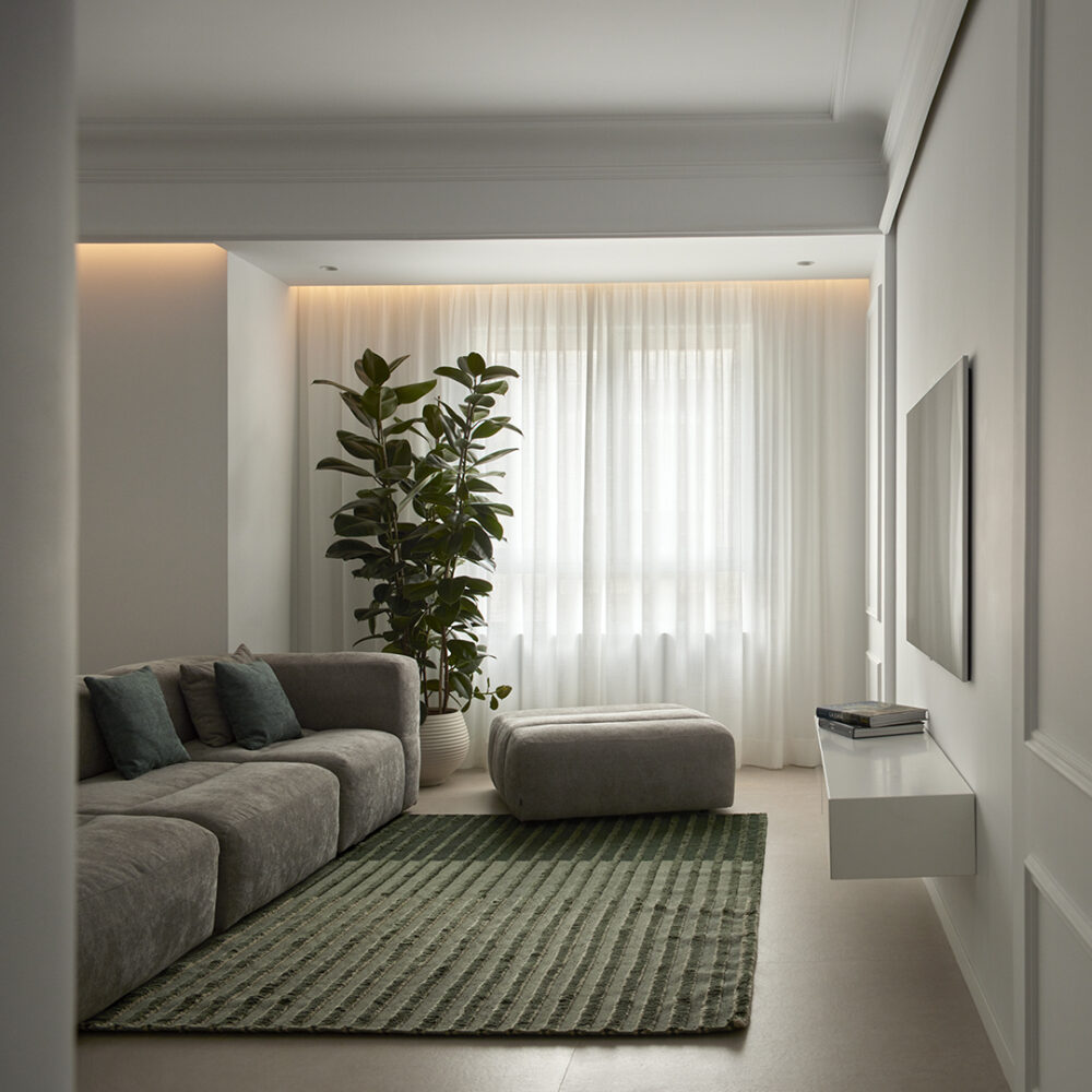 Salón con sofa modular y alfombra verde en vivienda La Petxina, por Studio Lucus