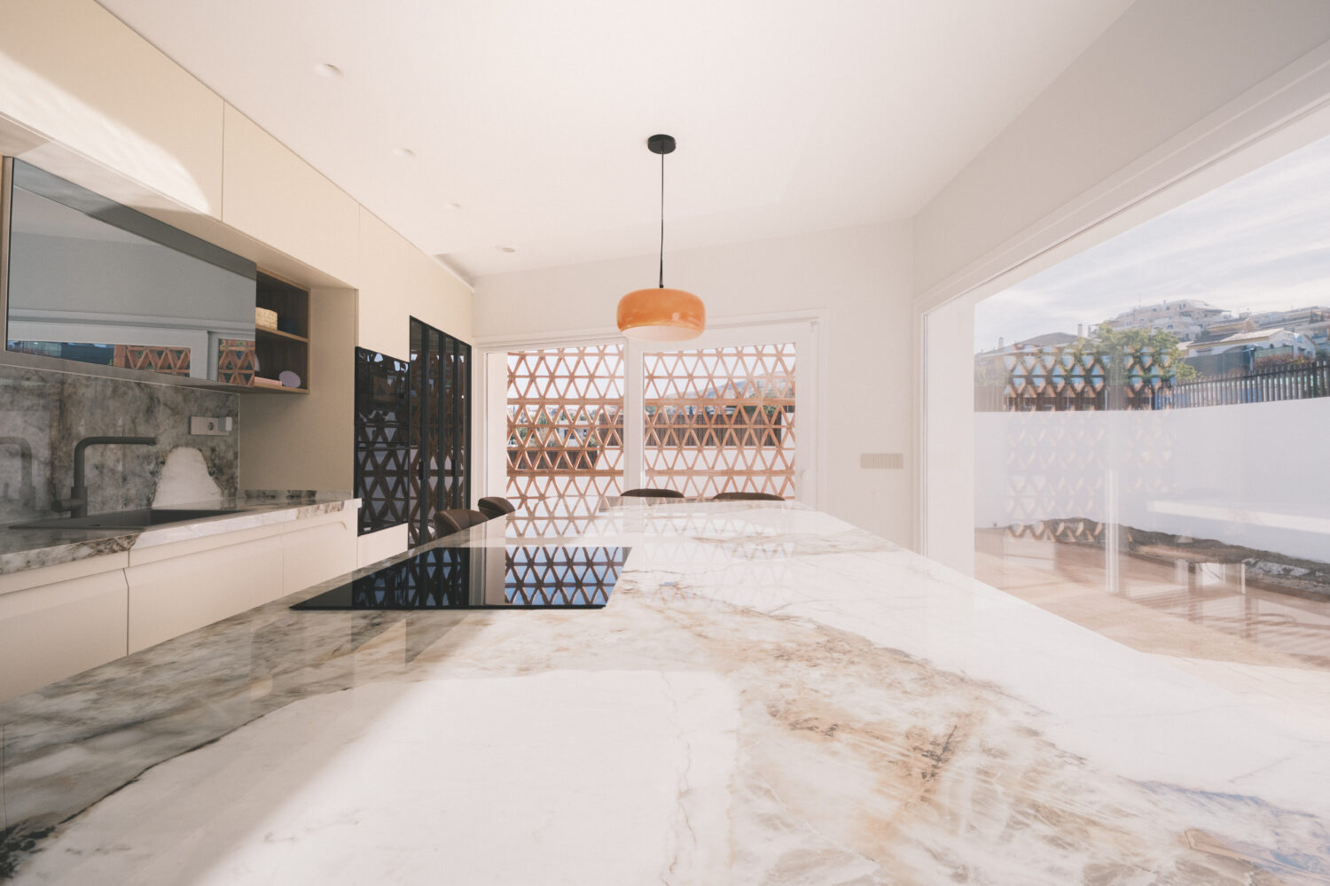 La planta baja se construye como una secuencia visual continua entre cocina, patio, salón y jardín.